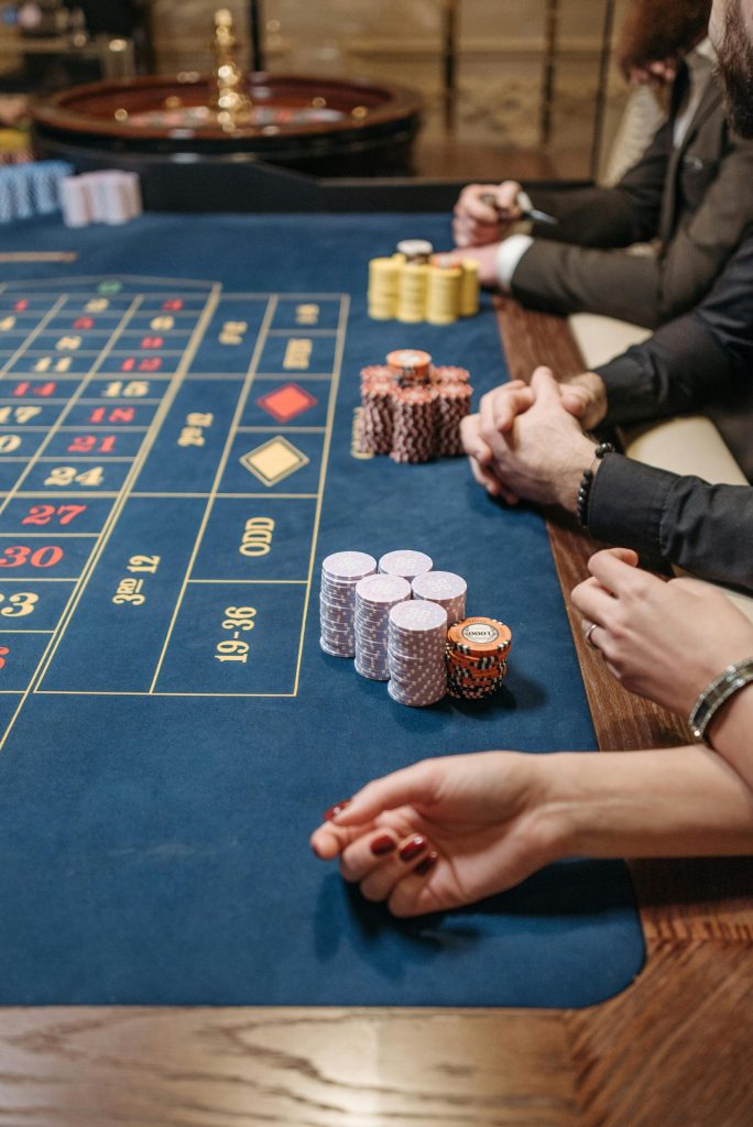 Spinbetclub Players engaged at a casino roulette table with colorful chips, showcasing the thrill of gambling.